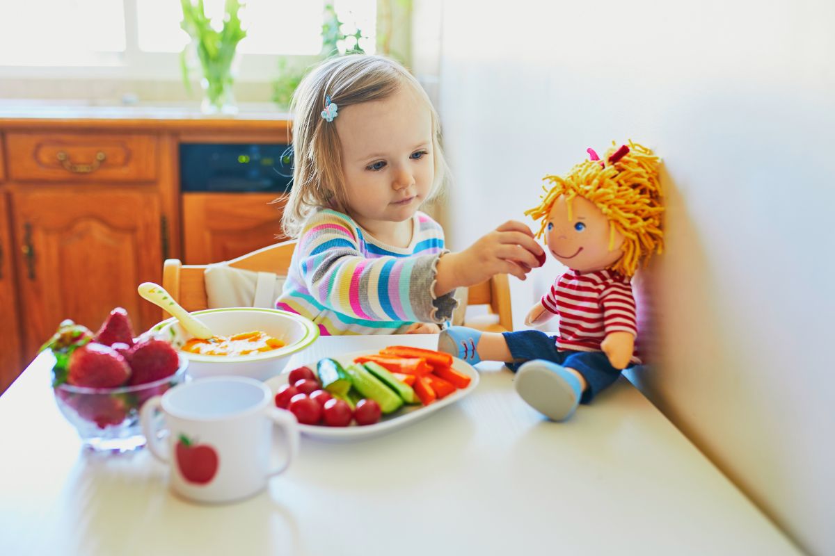Toddler eating fruit and feeding to her doll